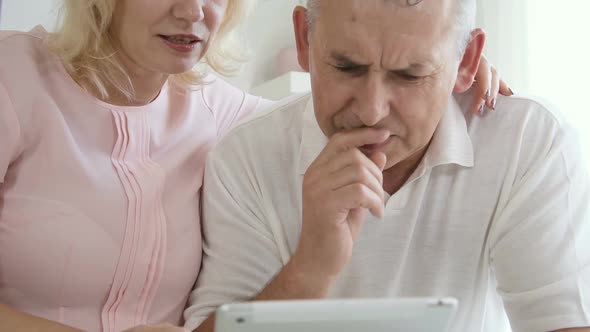 Front View of American Husband and Wife Watch at Gadget Screen with Smiles