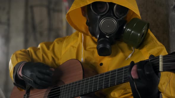 Close Up of Unrecognizable Young Man or Woman in Yellow Protective Suit and Gas Mask Sits on Floor