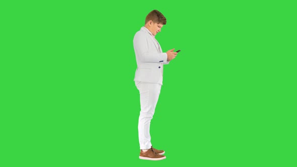 Young Teenager Boy in Business Suit Using Mobile Phone on a Green Screen Chroma Key