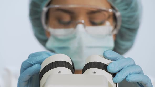 Biracial Female Researcher Adjusting Microscope Lenses, Conducting Research