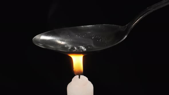 Cooking Heroin on a Spoon Over the Flame of Candle. Prepares a Dose. Hard Drugs