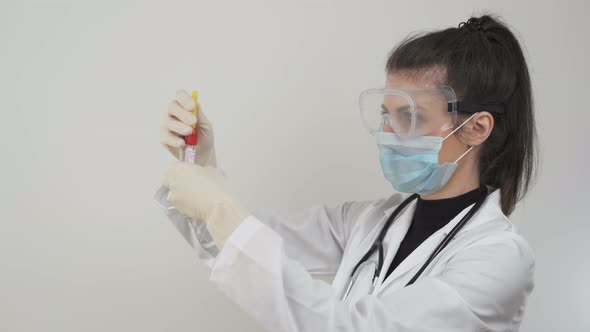 Female Doctor with Protective Face Mask and Glasses Testing Blood Samples for Deadly Coronavirus