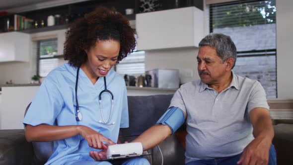 Senior mixed race man with female doctor home visiting taking blood pressure