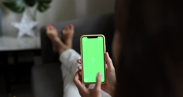 Young woman using mobile phone with chroma key at home when resting on sofa at home