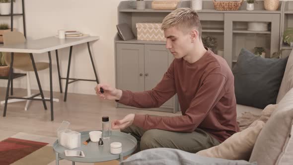 Young Man with Stylish Hairstyle Applying Nail Polish