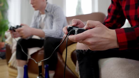 Closeup of Male Hands Using Game Controller with Blurred Concentrated Man Gaming at Background