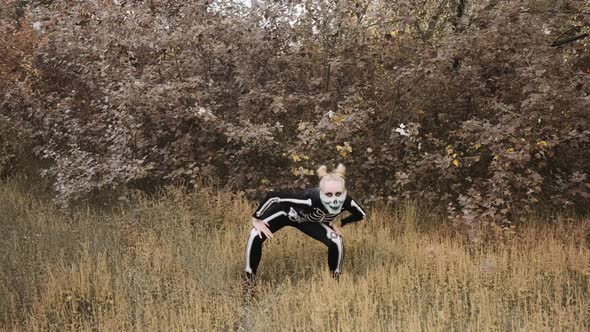 A girl with a scary make-up in a skeleton costume, a mask with rhinestones in a gloomy autumn forest