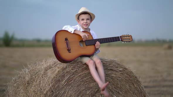 Little Boy on a Haystack with a Guitar