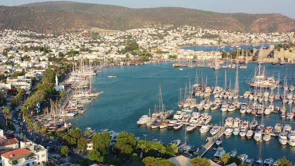 aerial drone flying across the Bodrum Marina with large sailboats docked in the Aegean Sea of Mugla