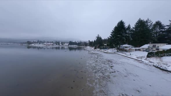 Snowy Shoreline Of Beach And Marina Of Sechelt Inlet During Winter In Canada. - aerial FPV