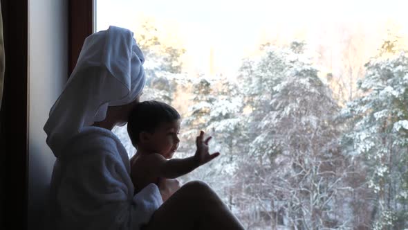 Mom and Son Sitting on the Window in a Bathrobe