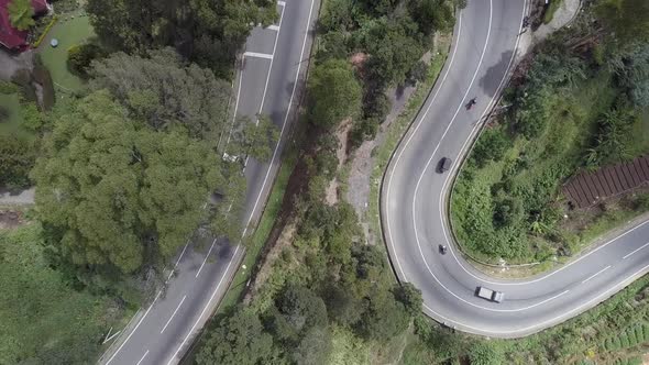 Steep Serpentine with Small Cars Passing Rural Houses