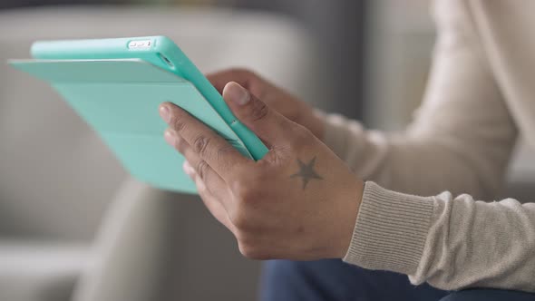 Closeup of Unrecognizable African American Man Texting on Tablet Indoors