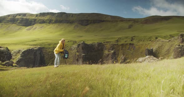 Young hiker gets ready for the path over green mountain landscape