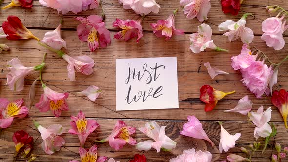 JUST LOVE card near flowers on a wooden table top view