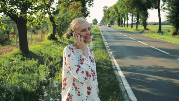 Young Lady Speaking on Phone While Hitchhiking.