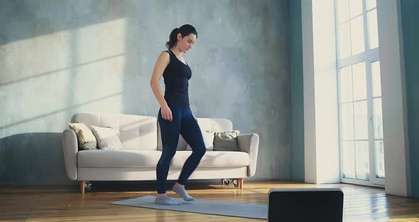 Stylish Woman Does Dynamic Lunges Watching Video on Laptop