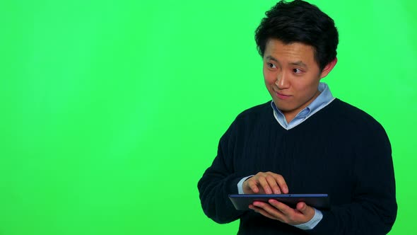 A Young Asian Man Works on a Tablet - Green Screen Studio