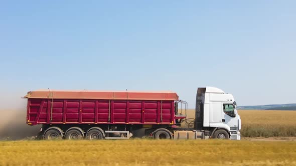 Aerial View of Cargo Truck Driving on Dirt Road Between Agricultural Wheat Fields Making Lot of Dust