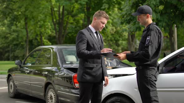 Upset Businessman Signing Accident Protocol With Cop, Auto Collision, Insurance