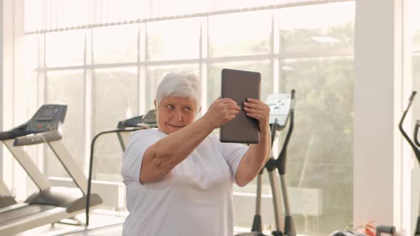 An Elderly Woman is Photographed on a Tablet Video Call Rest After Training Sends Greetings to