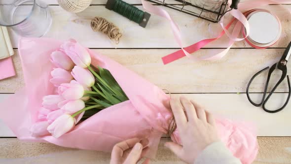 Step by step. Florist wrapping pink tulips in bouquet