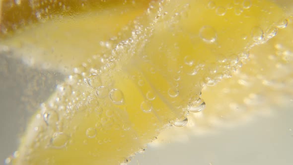 Fresh Lemon is Added to a Glass of Sparkling Ice Water Making a Refreshing Soft Drink