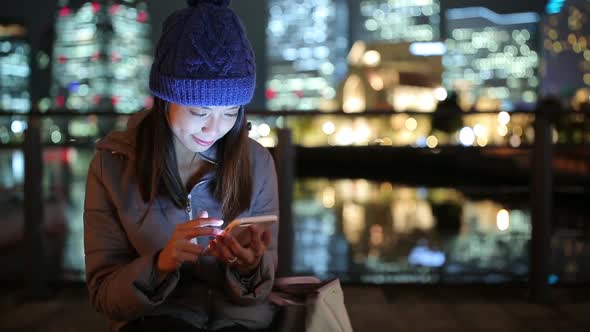 Woman using mobile phone in Yokohama city at night