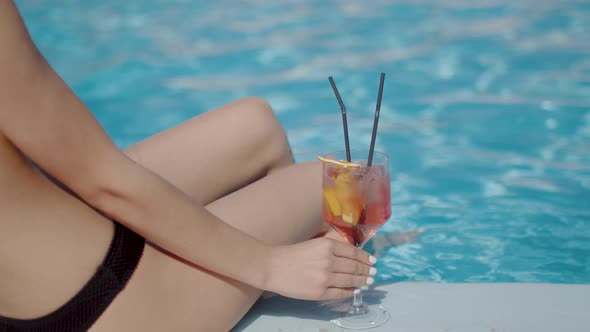 Woman's Legs Sitting By the Pool with a Cocktail