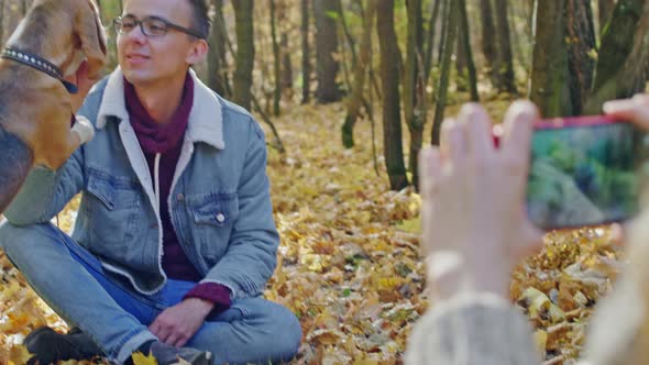 Smiling guy with a dog posing for a photo in autumn forest