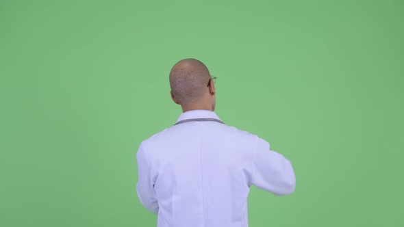 Rear View of Bald Multi Ethnic Man Doctor Pointing Finger