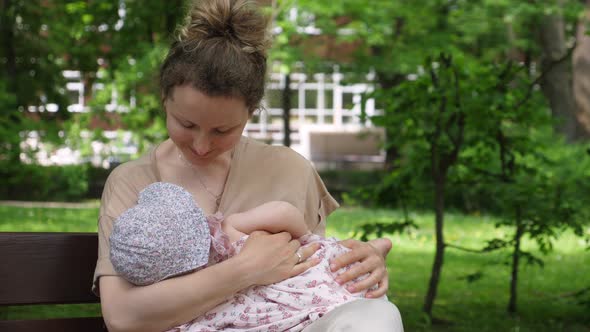 Young Mother Breastfeeding Her Baby in the Park.