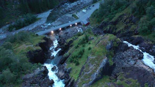 Top of Latefoss waterfall looking down at road and bridge with lights during dusk hour - Downwarding
