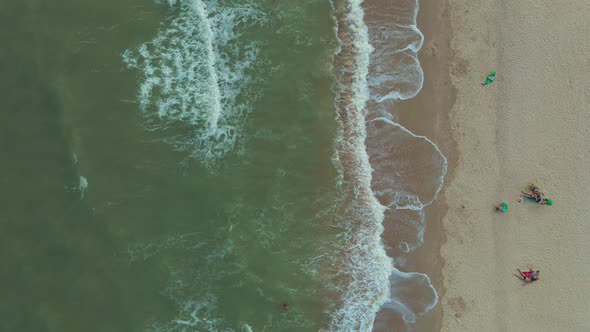 Waves Crashing on Sandy Beach with People on Beach