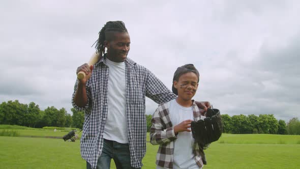 Positive African Dad and Son Walking on Field After Baseball Game