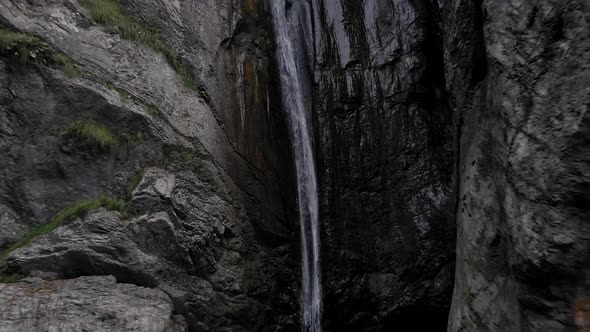 Waterfall down rocky mountain cliff, water falling into lake, cascade into abyss