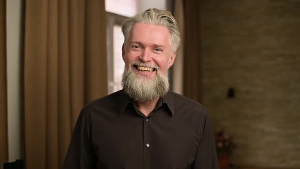 gray-haired bearded adult male smiling and showing positive disposition