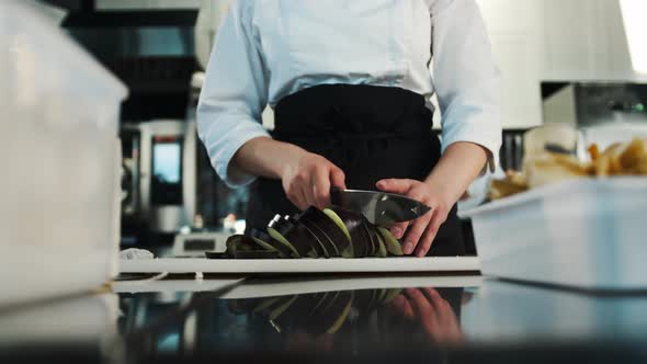 Close-up: The chef cuts an eggplant, preparing a delicious dish in a restaurant. The chef