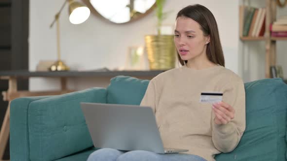 Online Shopping Success on Laptop By Young Woman on Sofa