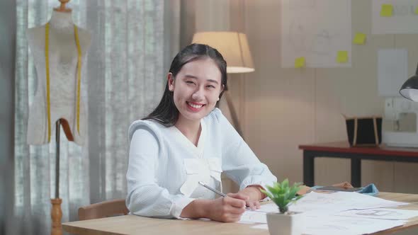Asian Woman Designer With Layout Bond Smile To Camera While Working With Laptop At The Office