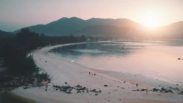 Aerial View Sunset Over Sandy Beach and Sea Mountains with Trees Golden Hour