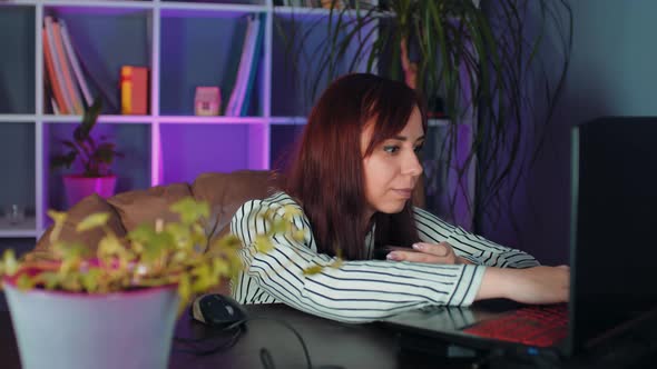 Young Woman Pays for Purchase on Internet Sitting in Armchair Before Computer in Office