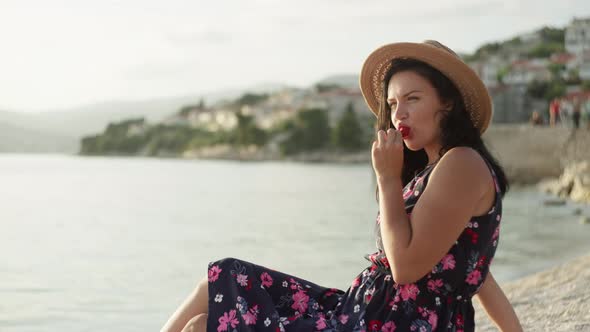 A Caucasian Girl Eats a Strawberry By the Ocean