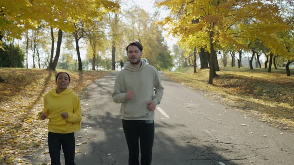 Man and Woman Running on a Track at the Park in Autumn Talking and Smiling