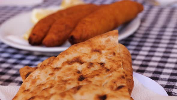 Close Up View Across Fresh Baked Flatbread Piled On Plate On Table Along With Other Dishes With Dips