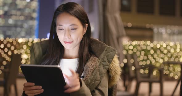 Woman use of tablet computer in coffee shop at night