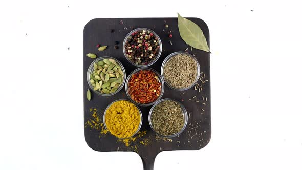 Different Indian Spices and Herbs Rotated on White Background in Glass Bowls