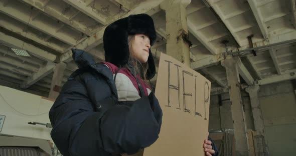 Homeless Caucasian Girl in Dirty Clothes Standing with the Help Cardboard and Asking for Help