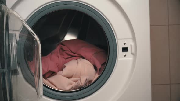 Women's Hands Put Clothes in a Modern Washing Machine