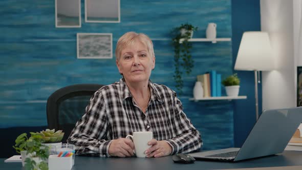 Senior Focused Woman Looking at Camera Sitting in Workplace